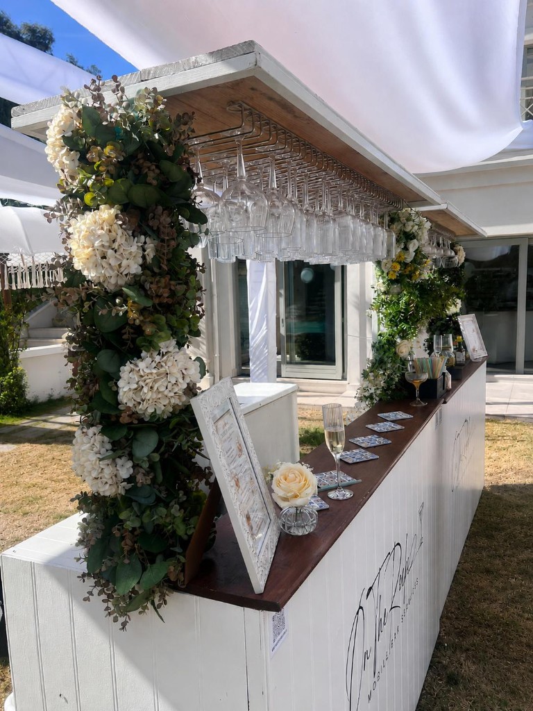 White mobile bar with floral decor at an outdoor event